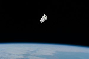 An astronaut floats in space above the Earth.